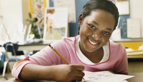 Portrait of a Schoolgirl Writing in Her Exercise Book in a Classroom