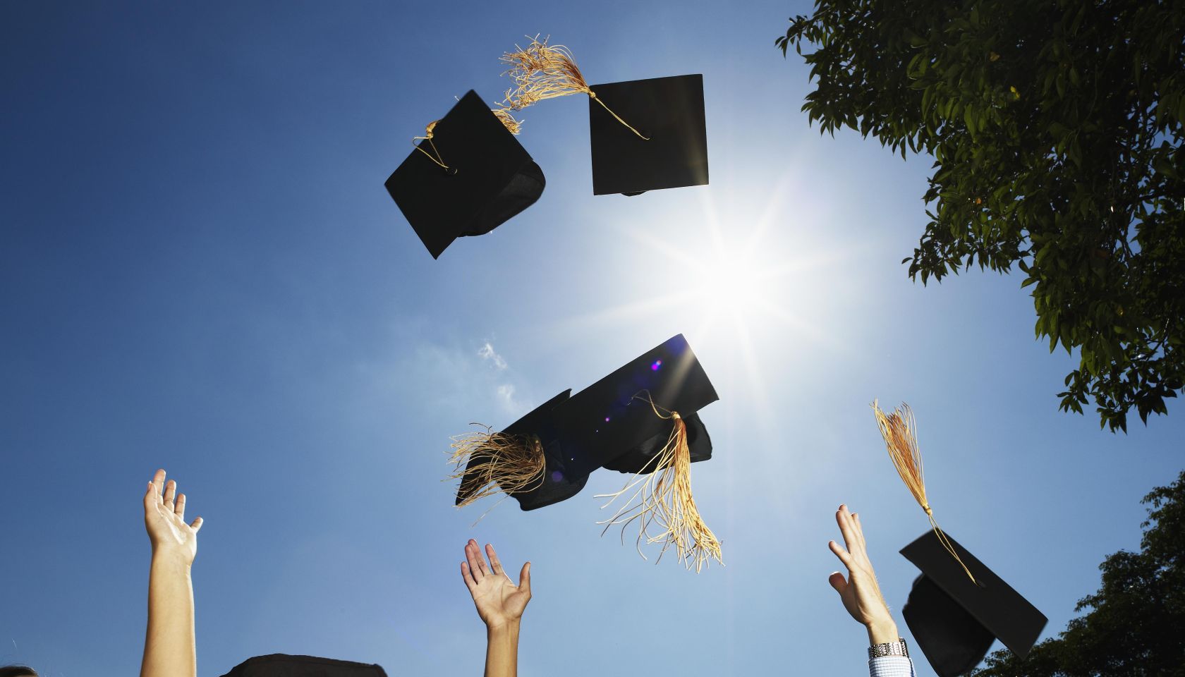Group of graduates throwing mortar boards in air