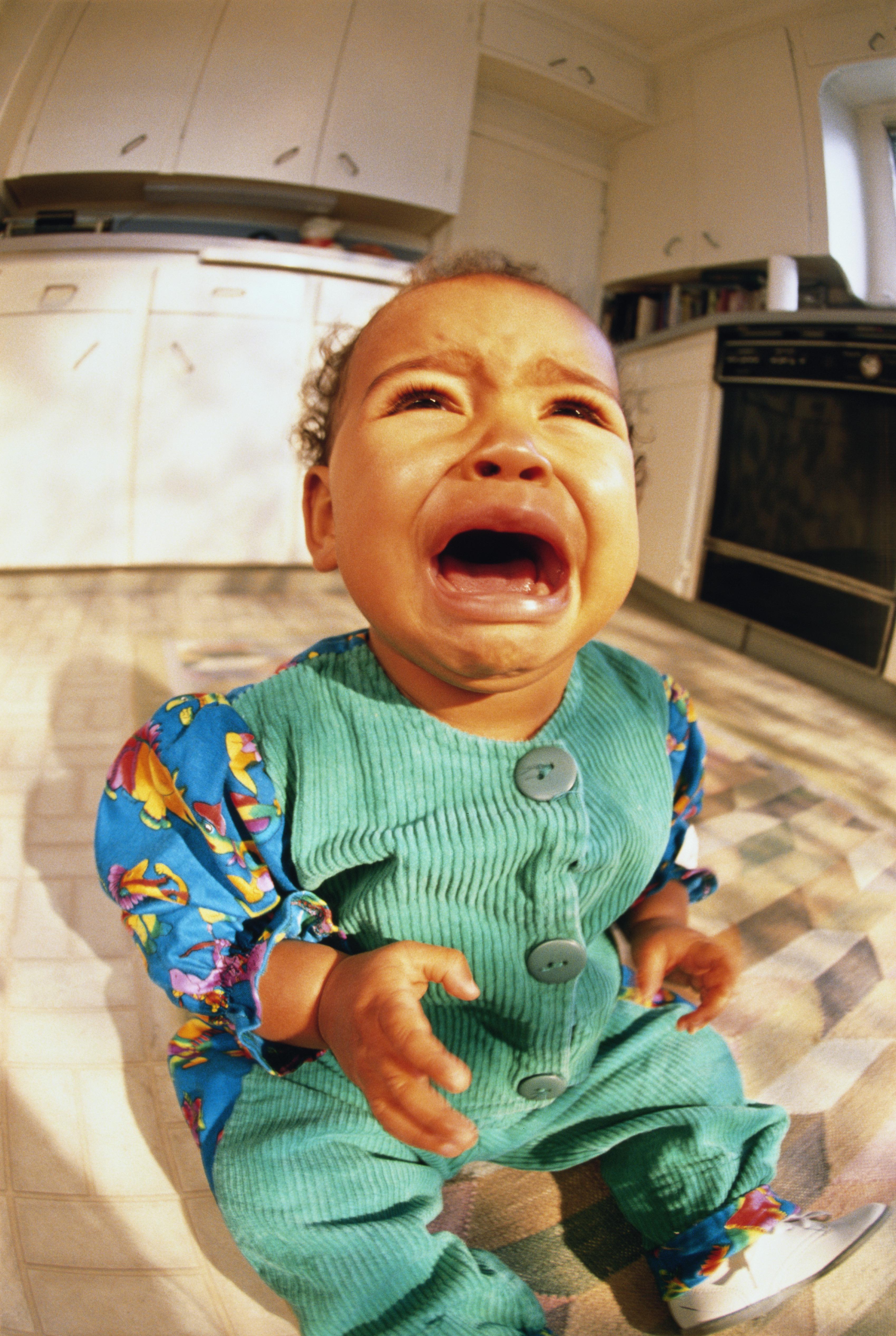 Baby boy (6-9 mo) sitting on kitchen floor, crying (wide angle)