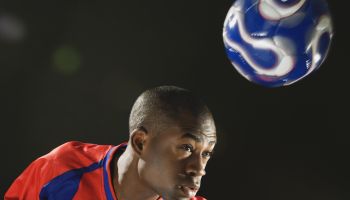 African American man bouncing soccer ball on head