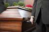 Religion, death and dolor - coffin bearer carrying casket at funeral to cemetery
