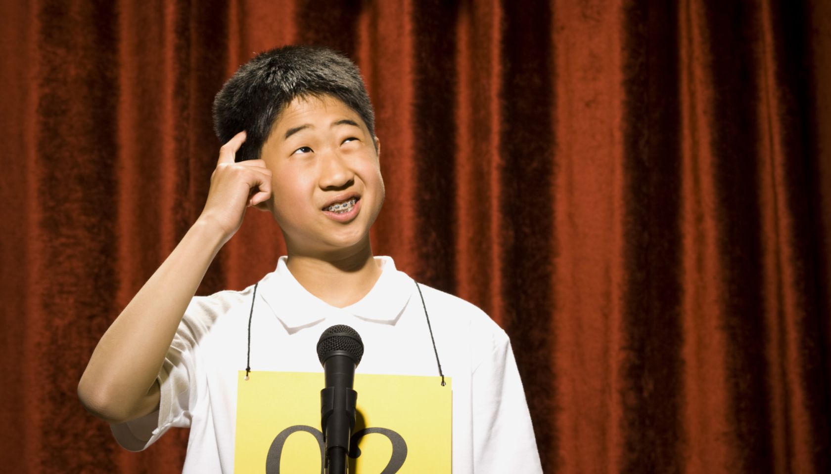 Boy contestant standing at microphone thinking