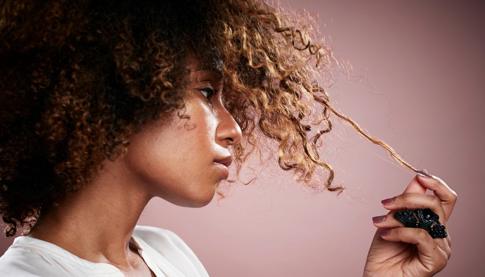 Portrait of young woman pulling on strand of curly hair