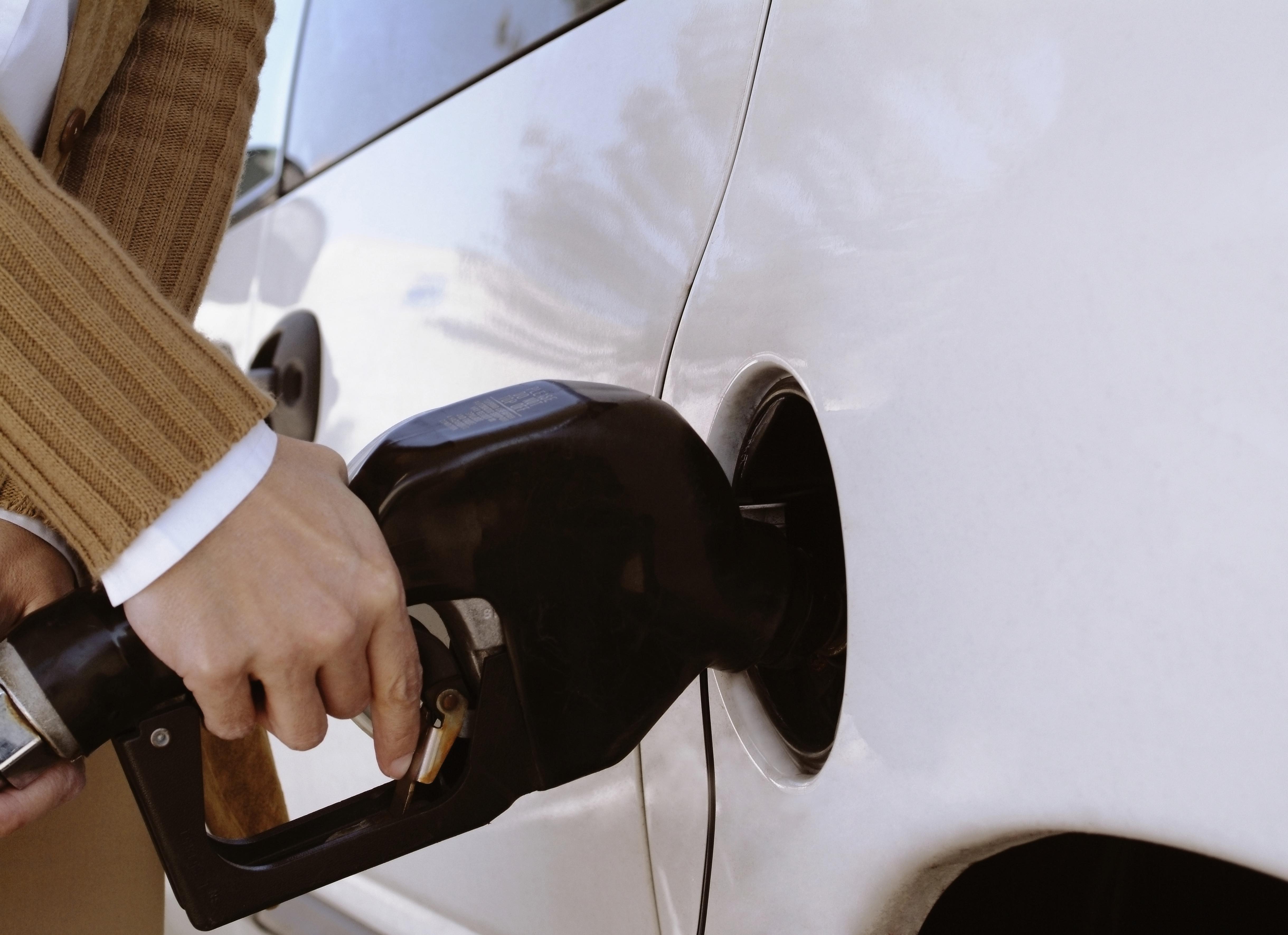 Woman putting gas in the tank of her car, extreme close-up
