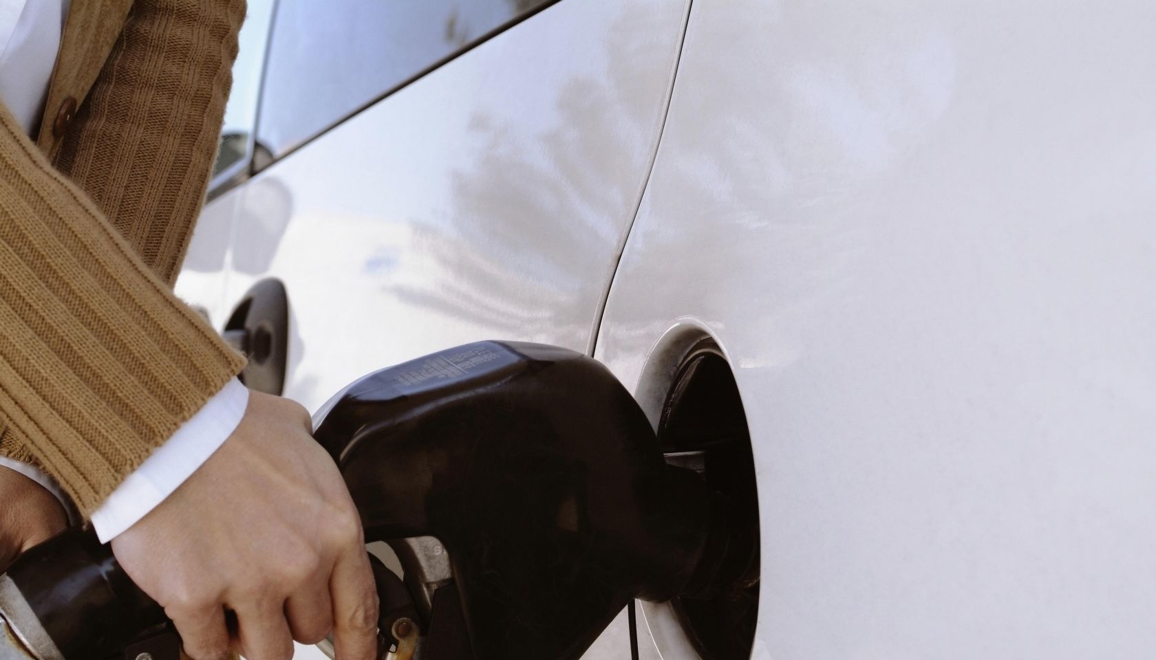 Woman putting gas in the tank of her car, extreme close-up