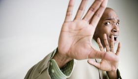 African businessman cowering with hands up