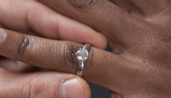 Close up of man putting engagement ring on girlfriend