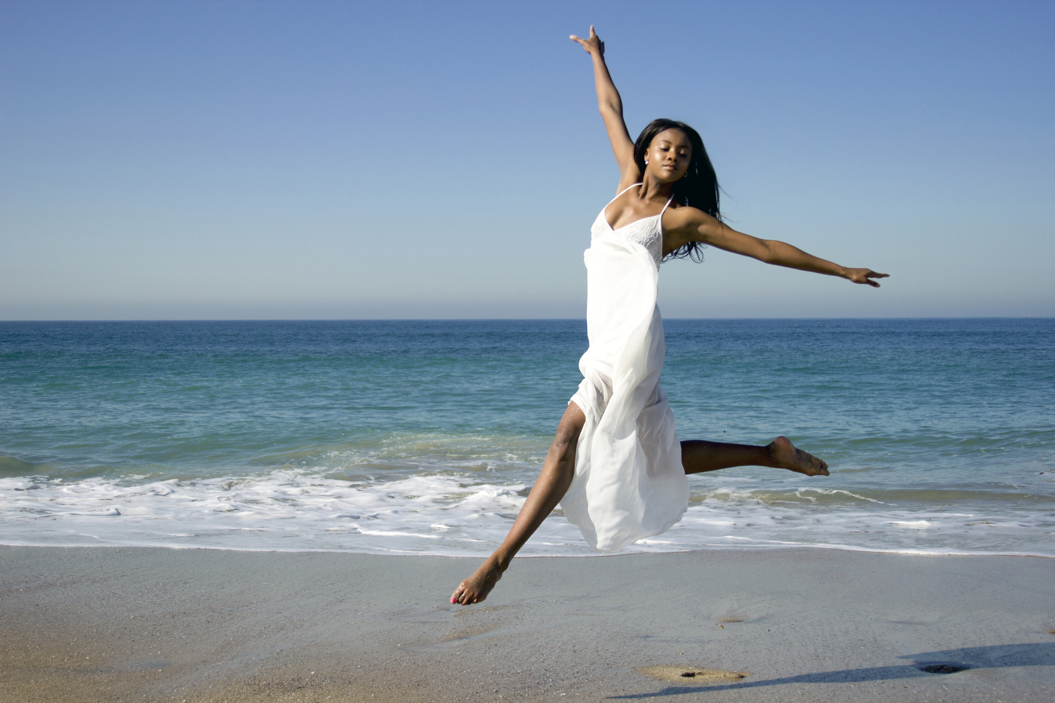 Young female dancer leaping mid air on beach