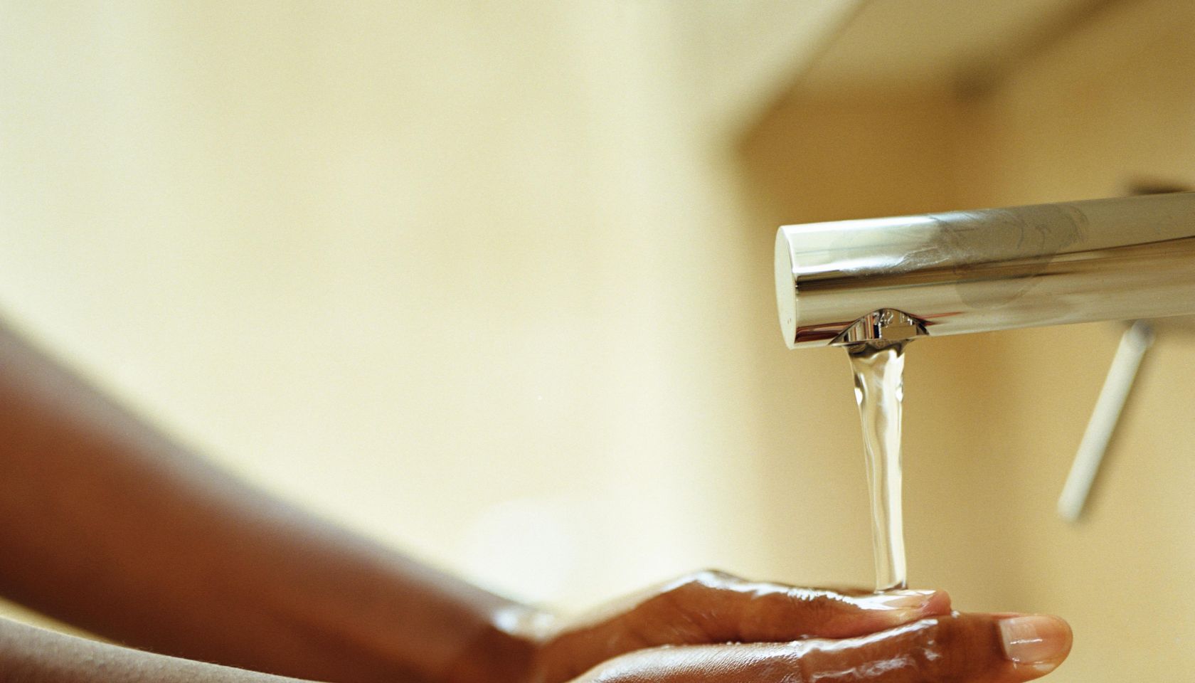 Young woman washing hands under running tap, close-up