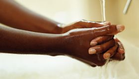 Young woman washing hands under running tap, close-up
