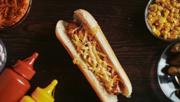 Hot dog on a wooden board. American fast food with sausage, cheese and mustard on a wooden table. Photo from the top.