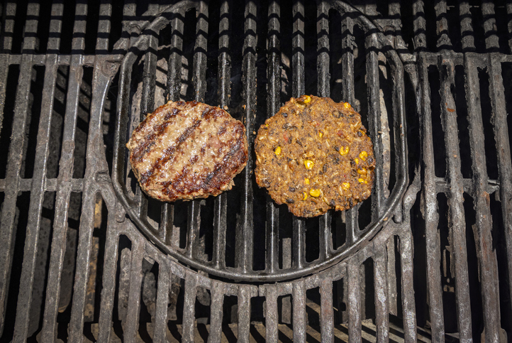 A grill with an animal based hamburger on the left and a plant based vegan hamburger on the right.