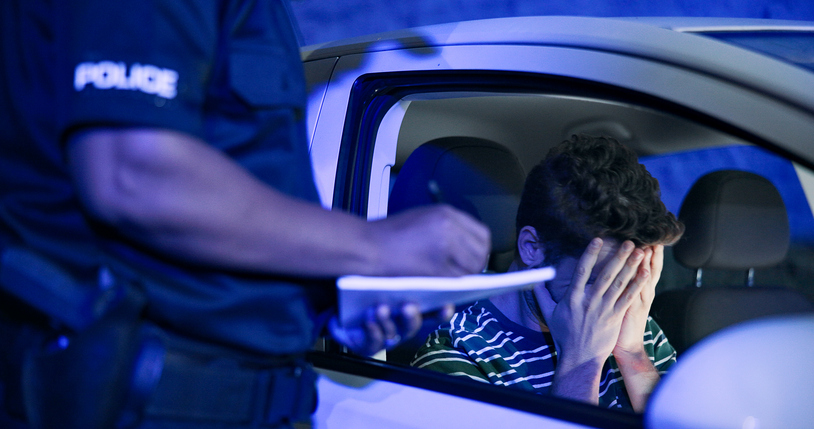 Traffic stop, man and frustrated in car with police, lights and stress for drunk driving or speeding at night. Travel, transport and driver in vehicle with highway patrol, ticket or street compliance