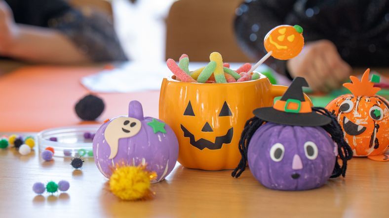 Colorful Halloween decorations, crafts and candy in a pumpkin-shaped mug on a table. Halloween