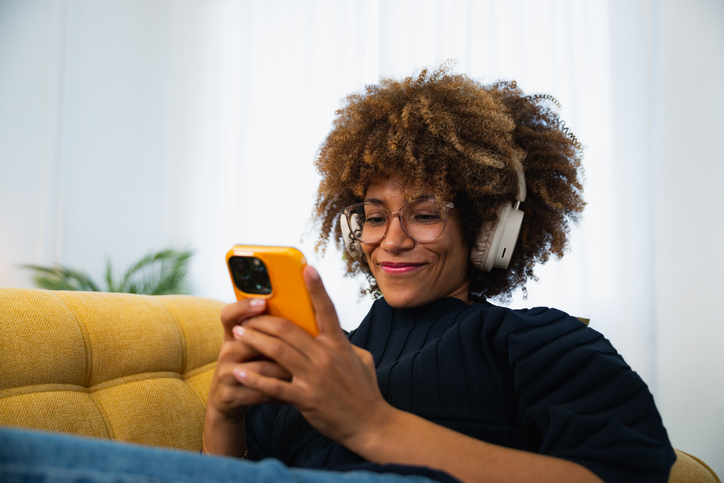 Smiling woman listening to music and texting on smartphone