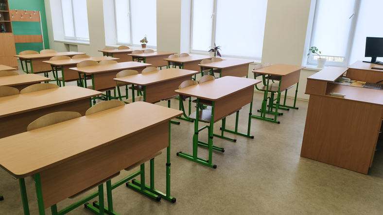 classroom interior with wooden desks aligned in rows and chairs