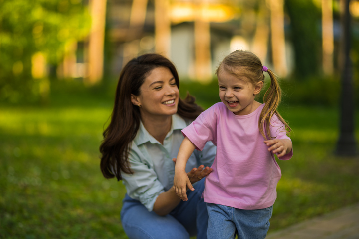 Mother and daughter playing outdoors laughing together