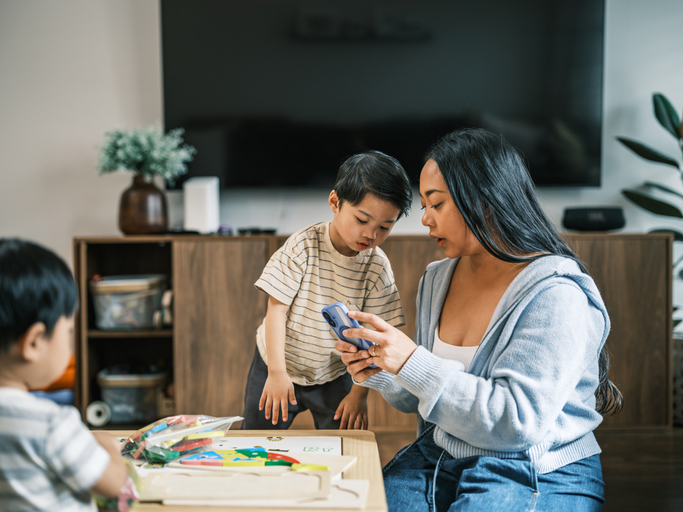 Young Asian mother and two young sons playing in living room