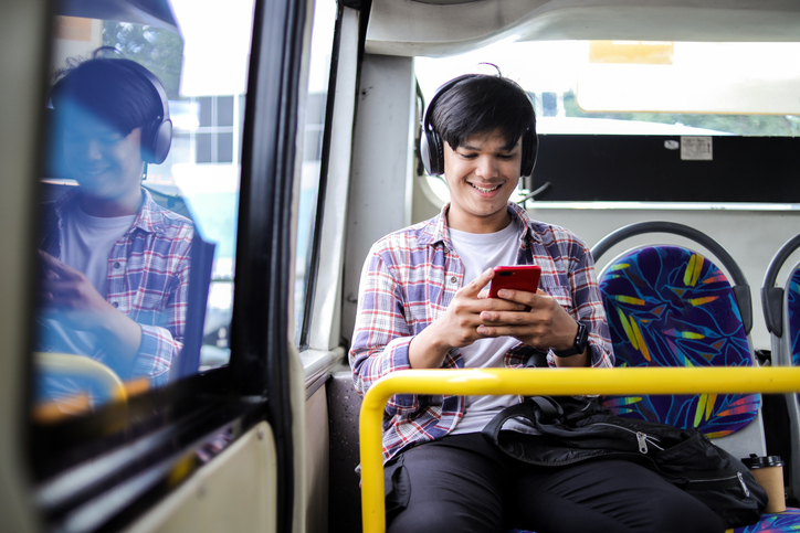 Young Asian Guy Using Mobile Phone While Riding in City Bus
