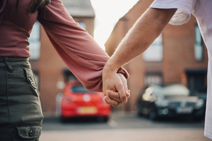 Couple holding hands outside modern suburban homes