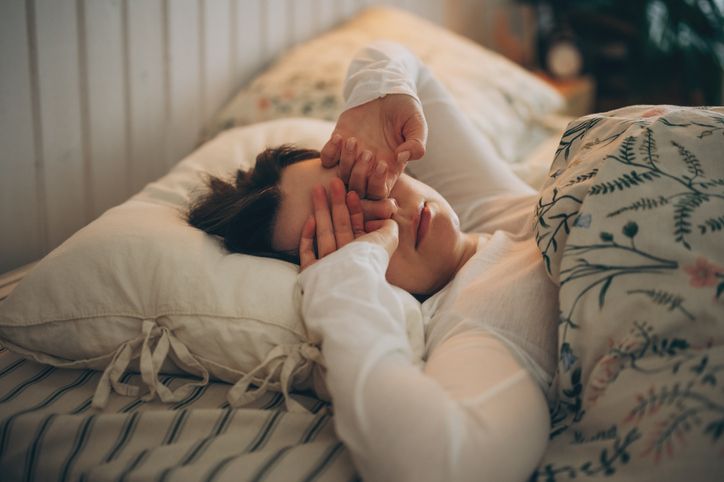 Sleepless young woman suffering from insomnia, covering eyes with hands