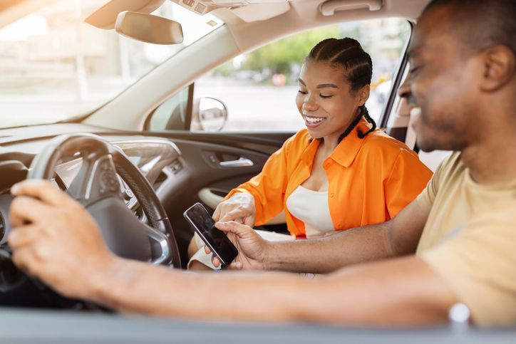 Young Black couple using smartphone together inside car